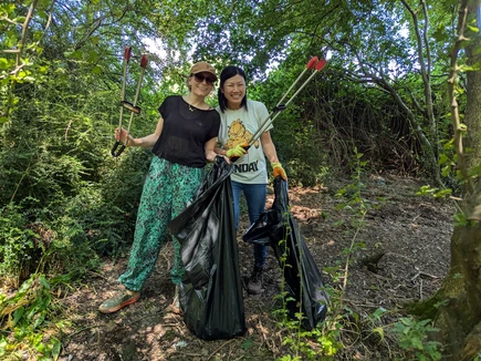 Two female volunteers litter picking in a local park